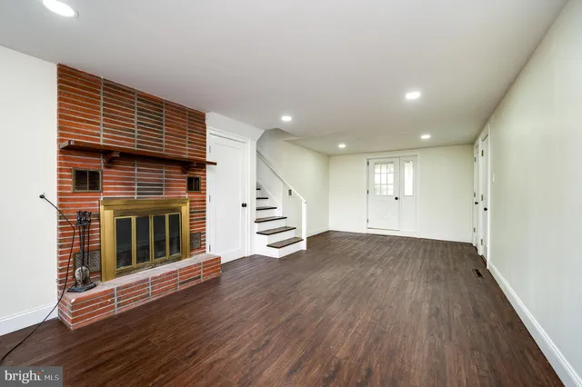 an empty room with wooden floor fireplace and windows