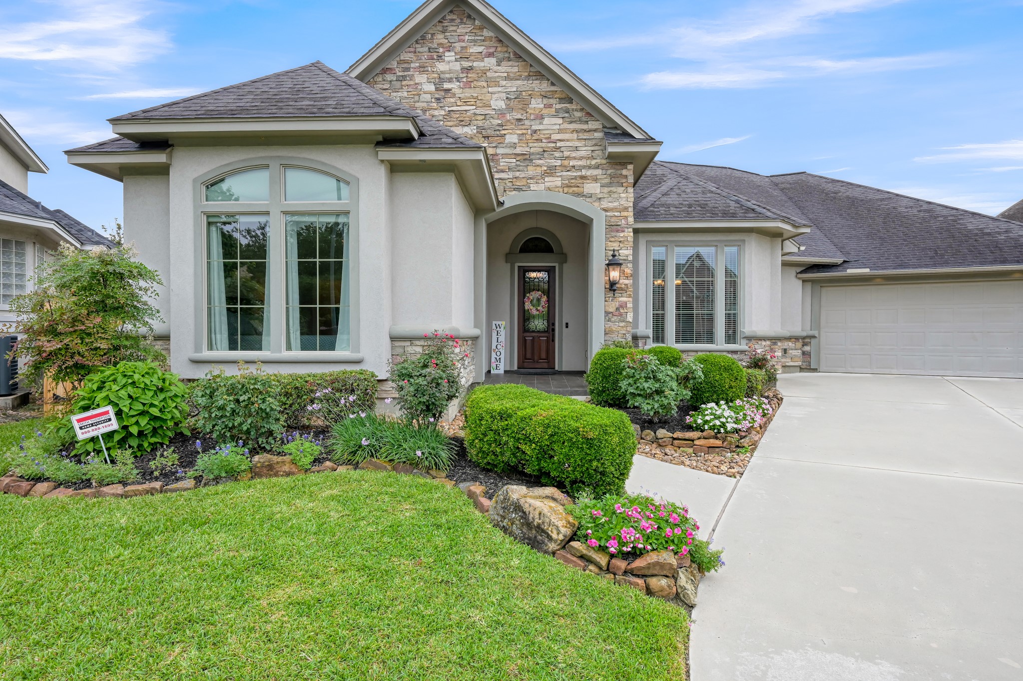 16318 Perry Pass Court Spring, TX 77379 - Photo 2 of 49 The exterior is stucco with stacked stone and features architectural interests including arched and framed windows. The raised landscaped beds are lined with stacked stone accented with larger rocks. The double-wide driveway has plenty of room for extra parking.