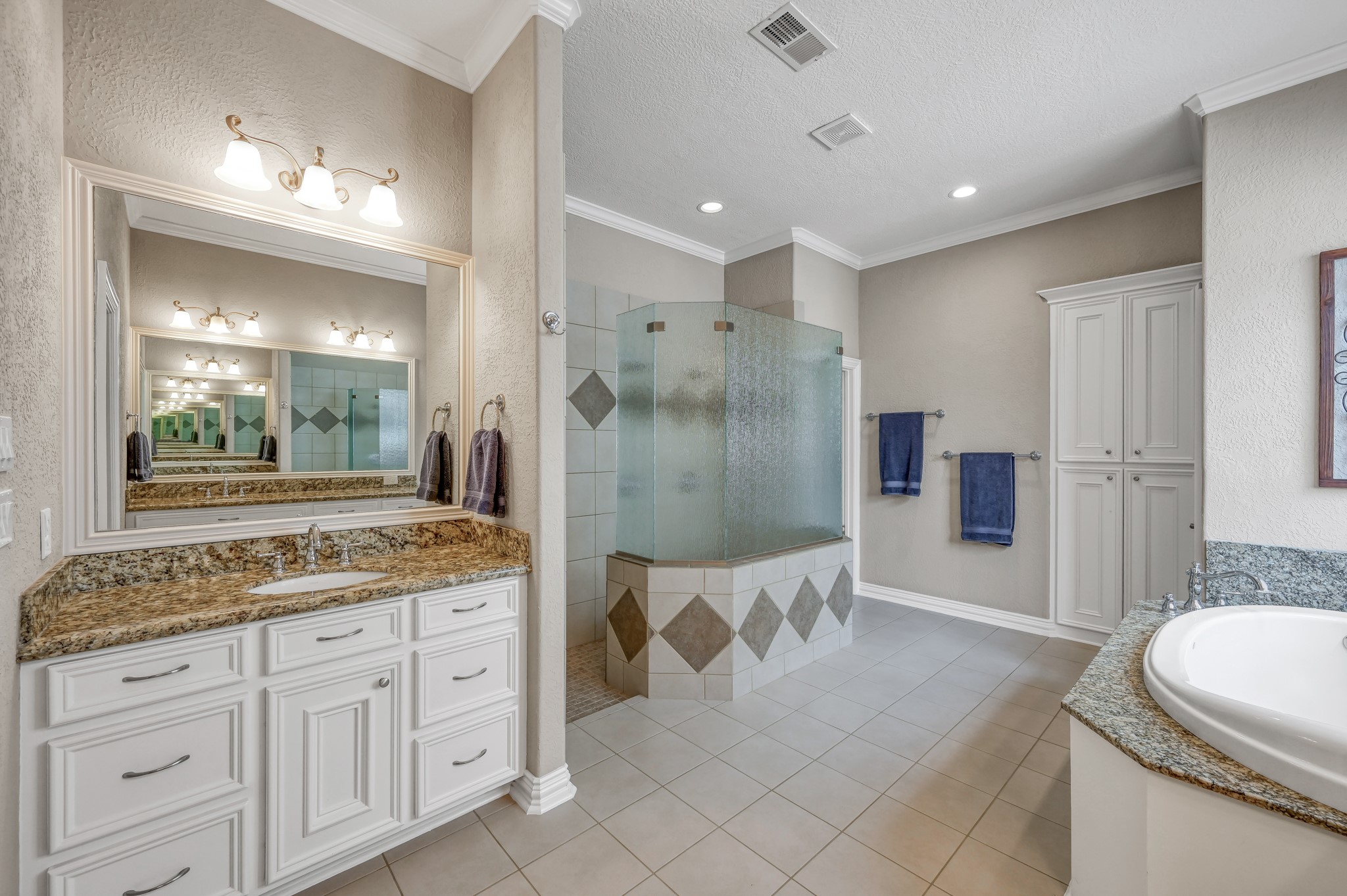 16318 Perry Pass Court Spring, TX 77379 - Photo 23 of 49 This spa-like bathroom features dual sinks with granite counters tops and an oversized walk-in shower with dual heads and a bench. There are tile floors and surround with a linen cabinet on the far wall.