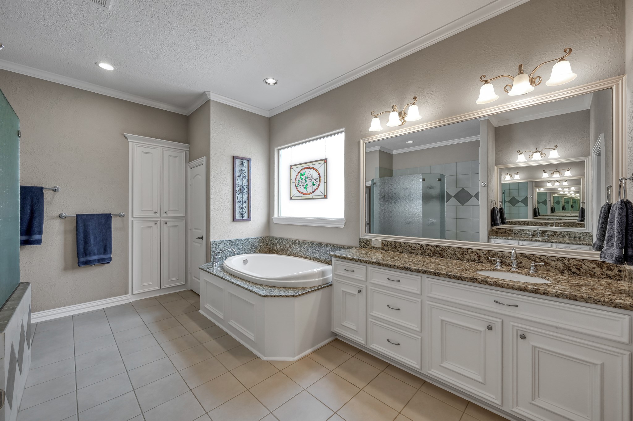 16318 Perry Pass Court Spring, TX 77379 - Photo 24 of 49 The large soaking tub has a granite surround and frosted garden window, letting in natural light in addition to the recessed lighting. The oversized vanity has a long counter top and framed mirror with plenty of cabinets and drawers to help stay organized.