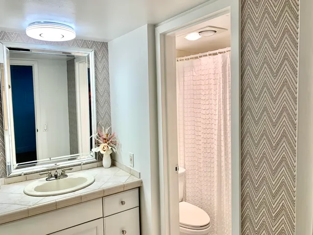 a bathroom with a granite countertop sink toilet and mirror