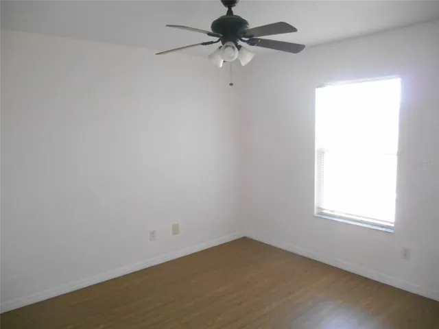 an empty room with a window and a fan