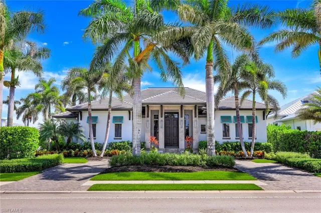a view of a brick house with a yard and palm trees