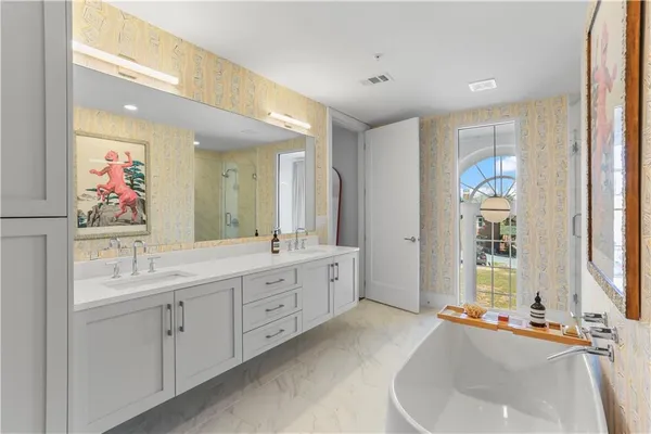 a spacious bathroom with a double vanity sink a large mirror a bathtub and window