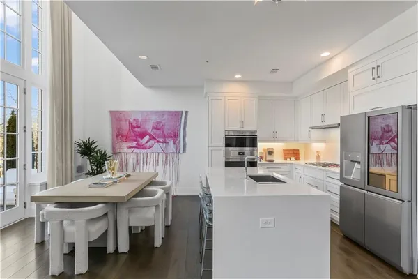 a kitchen with stainless steel appliances a microwave a dining table and chairs