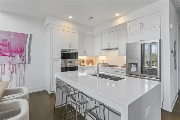 a kitchen with a sink a stove a refrigerator and white cabinets with wooden floor