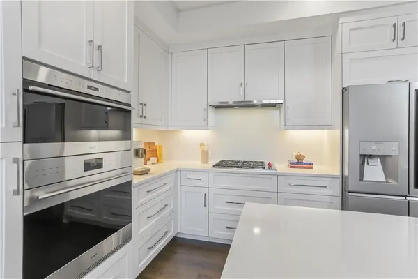 a kitchen with granite countertop white cabinets and stainless steel appliances