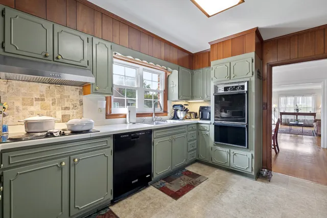 a kitchen with stainless steel appliances granite countertop a sink a stove a refrigerator cabinets and a window