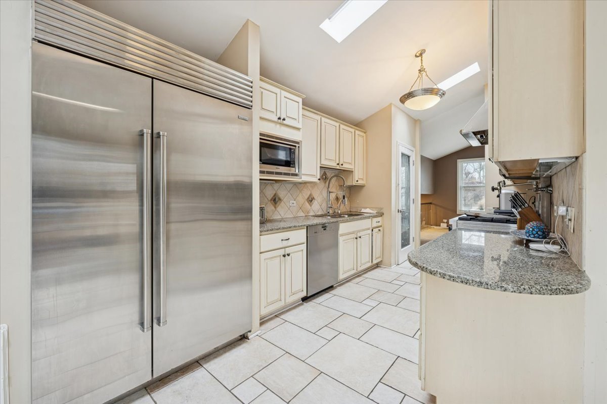 1908 McCraren Road Highland Park, IL 60035 - Photo 11 of 37 a kitchen with kitchen island granite countertop a refrigerator a sink and white cabinets