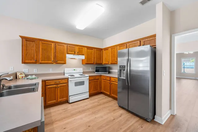 a kitchen with stainless steel appliances granite countertop a refrigerator a sink dishwasher a stove with wooden cabinets and a refrigerator