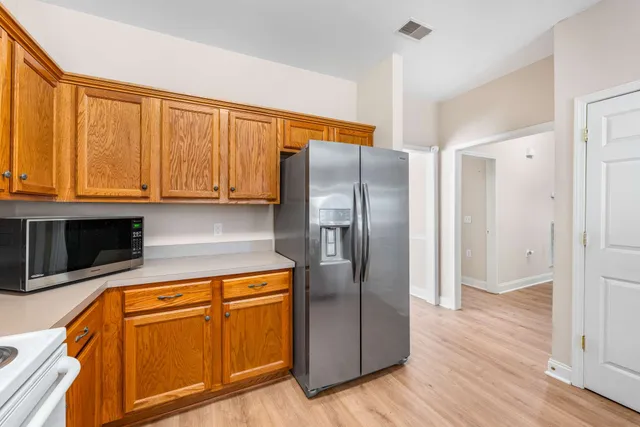 a kitchen with stainless steel appliances granite countertop a refrigerator a microwave oven cabinets and a wooden floor