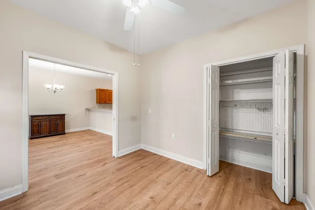 a view of an empty room with wooden floor fridge and a window