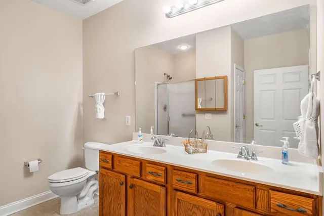 a bathroom with a double vanity sink toilet and mirror
