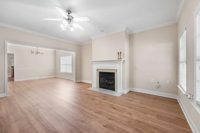 an empty room with windows fireplace and wooden floor