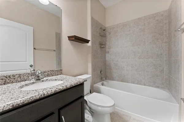 a bathroom with a granite countertop sink a toilet and bathtub