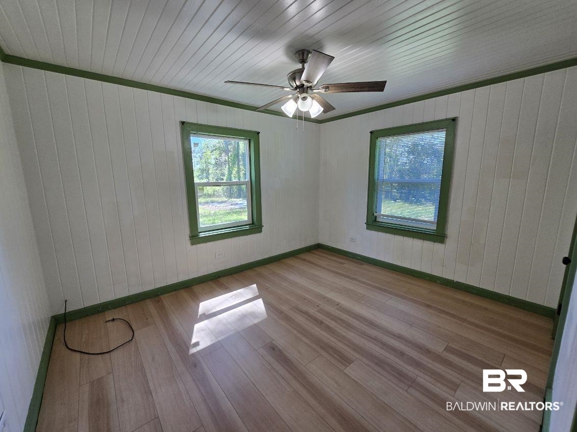 6464 Ridge Road Brewton, AL 36426 - Photo 12 of 14 Unfurnished room with wood walls, light wood finished floors, and ceiling fan
