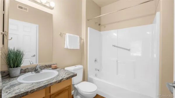 a bathroom with a granite countertop sink toilet a large mirror a shower and a bathtub
