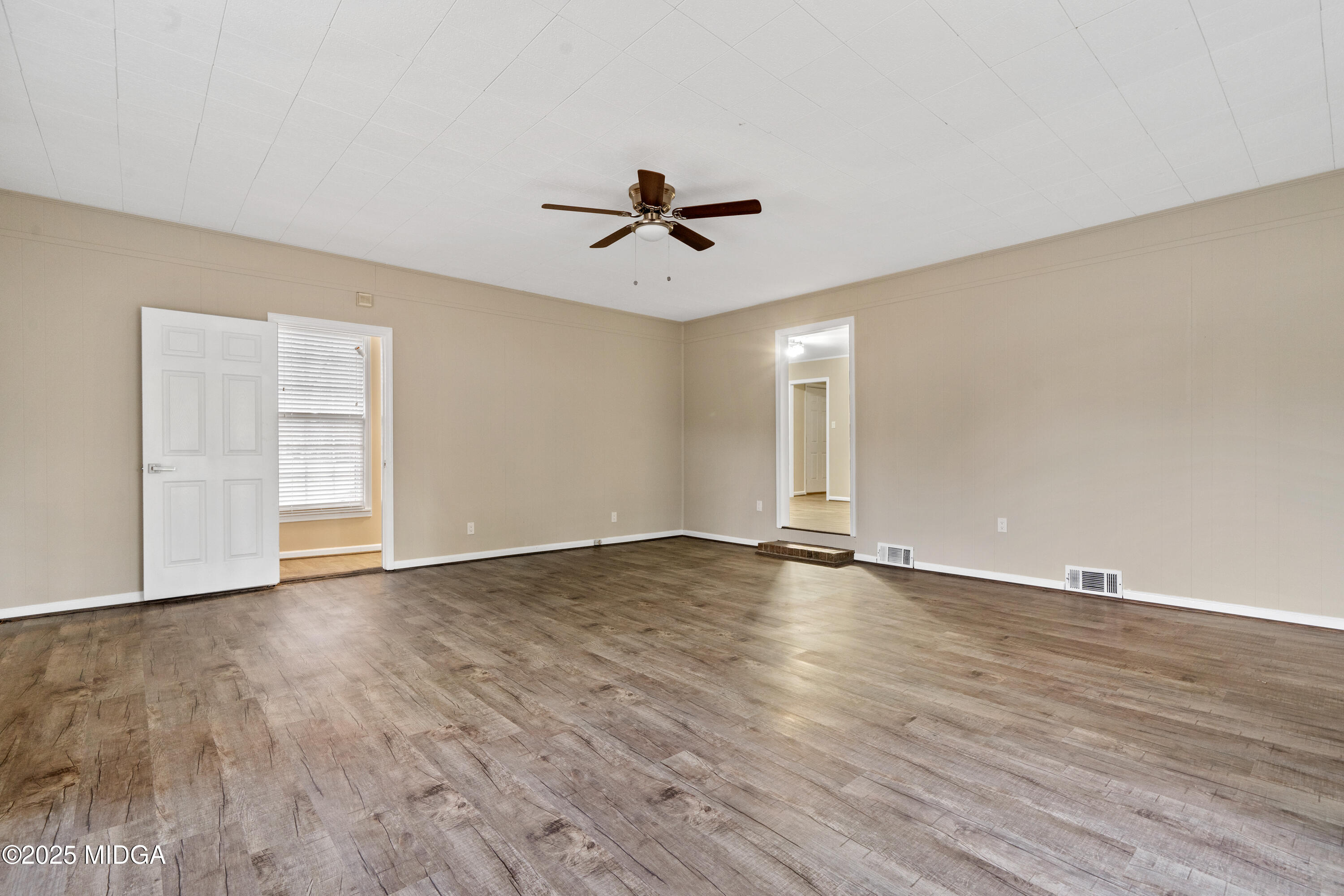 1303 Forest Hill Road Macon, GA 31210 - Photo 26 of 54 an empty room with wooden floor ceiling fan and windows
