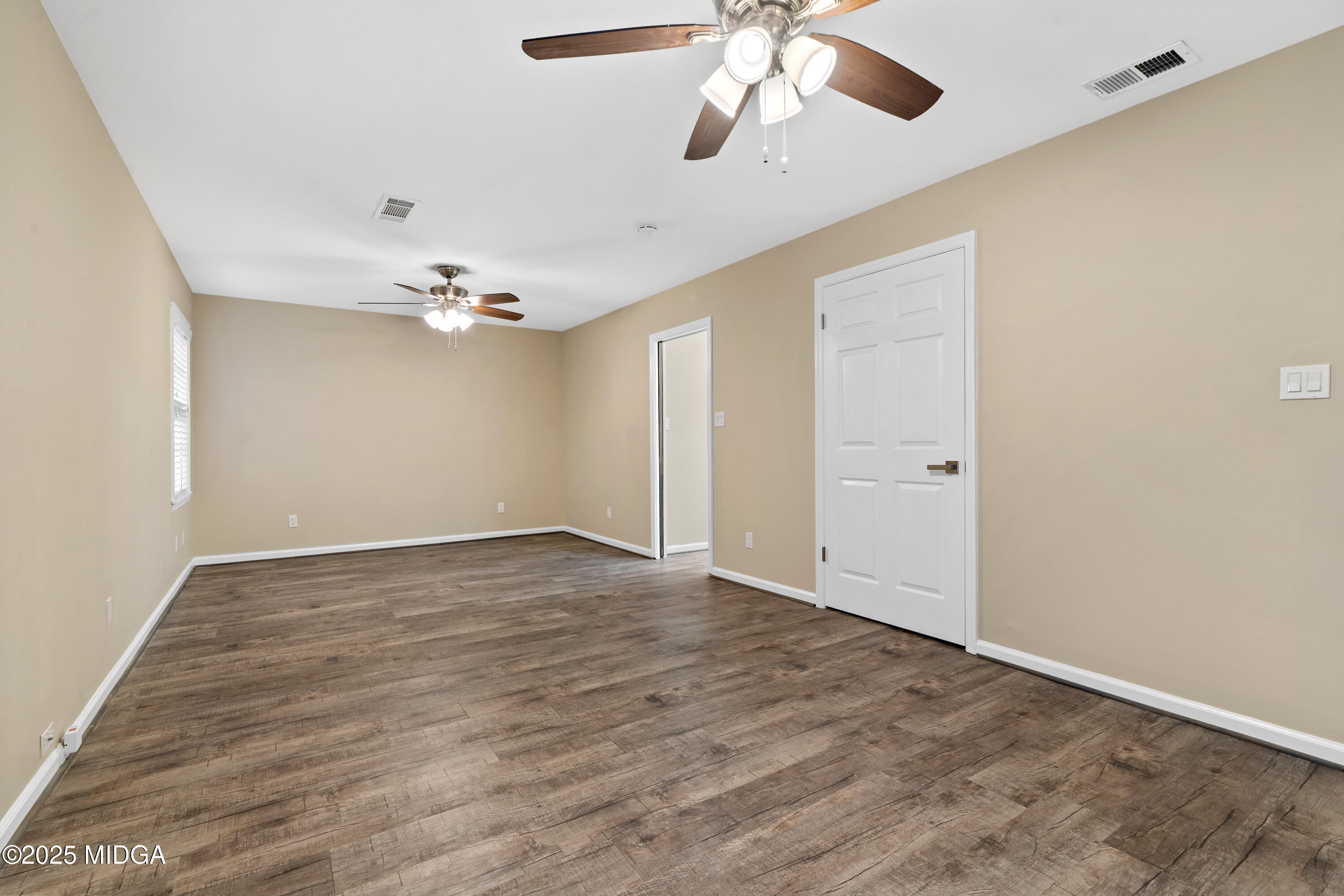 1303 Forest Hill Road Macon, GA 31210 - Photo 38 of 54 an empty room with a chandelier fan and wooden floor