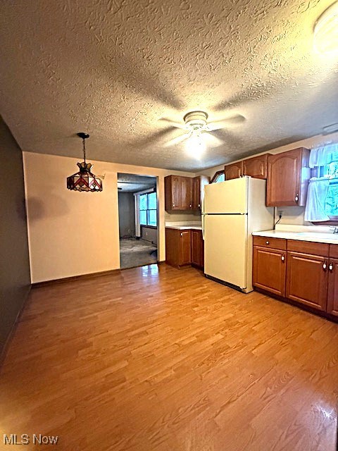Kitchen featuring freestanding refrigerator, light wood-style flooring, a ceiling fan, light countertops, and a sink