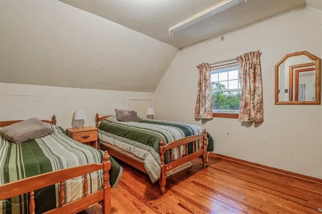 a bedroom with two beds and wooden floor