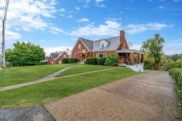 a view of a house with a big yard and large trees