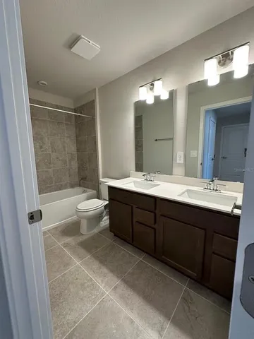a bathroom with a double vanity sink toilet mirror and bathtub