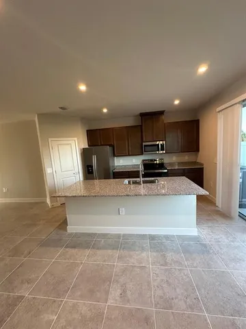 a large kitchen with stainless steel appliances granite countertop a stove a sink a microwave and a refrigerator