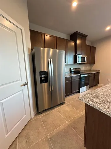 a kitchen with stainless steel appliances granite countertop a refrigerator and a sink