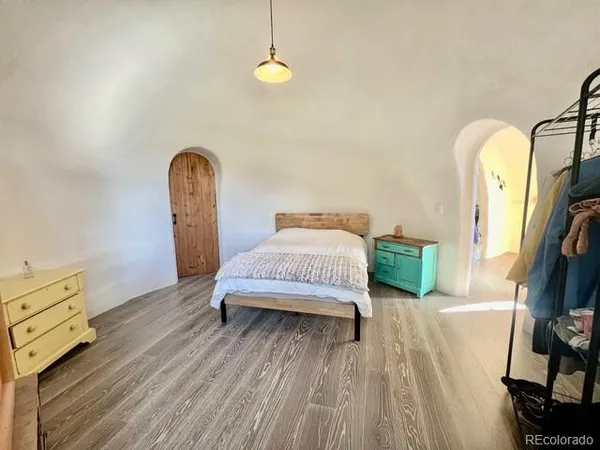 a spacious bedroom with a bed and a flat tv screen on dresser