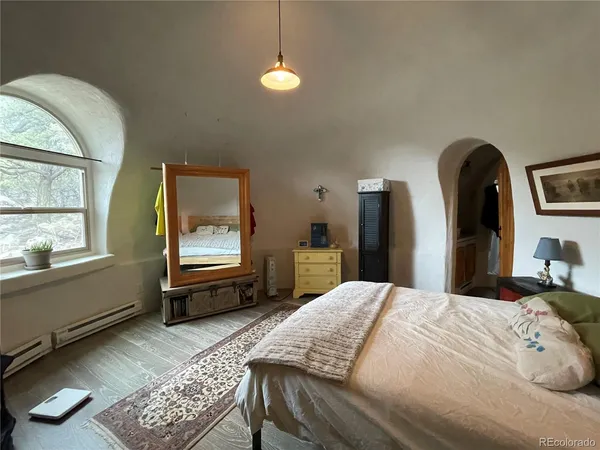 a bedroom with a bed a dresser and next to a window