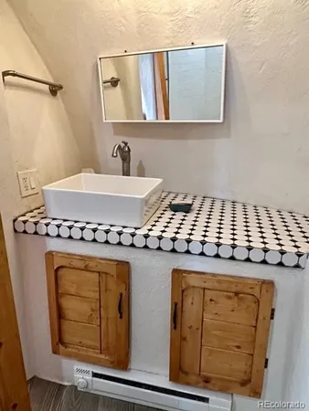a bathroom with a granite countertop sink a stove and a mirror