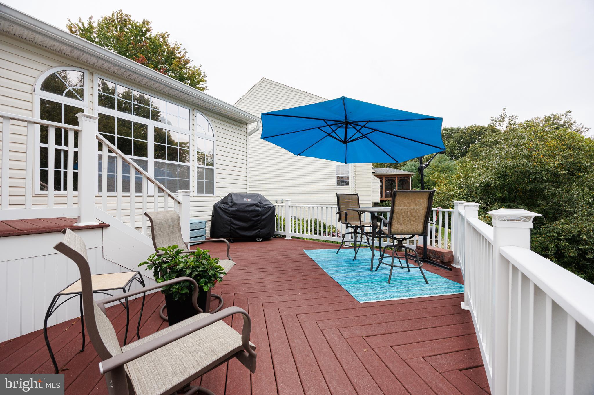 6265 White Birch Road Eldersburg, MD 21784 - Photo 4 of 17 a view of a patio with table and chairs under an umbrella with wooden floor