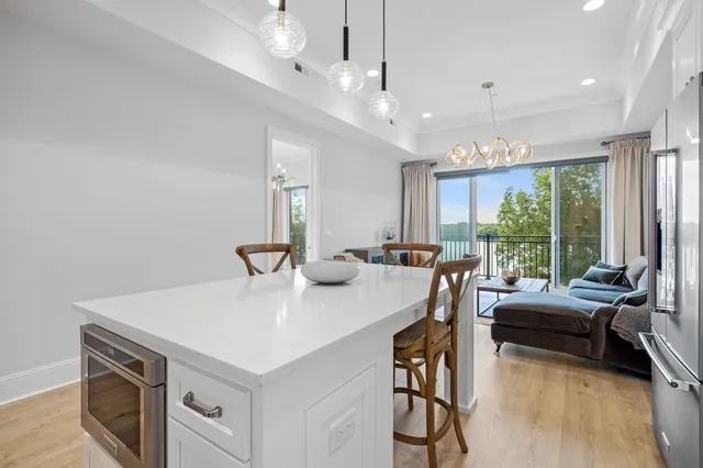 a kitchen with stainless steel appliances granite countertop a dining table chairs refrigerator and microwave