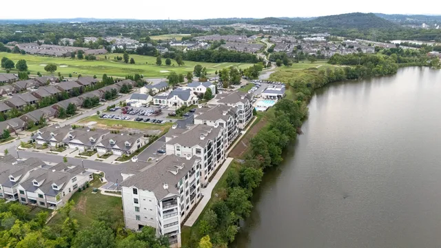 an aerial view of residential houses with outdoor space and lake view
