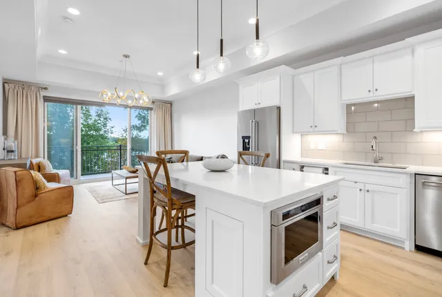 a living room with furniture a refrigerator and kitchen view