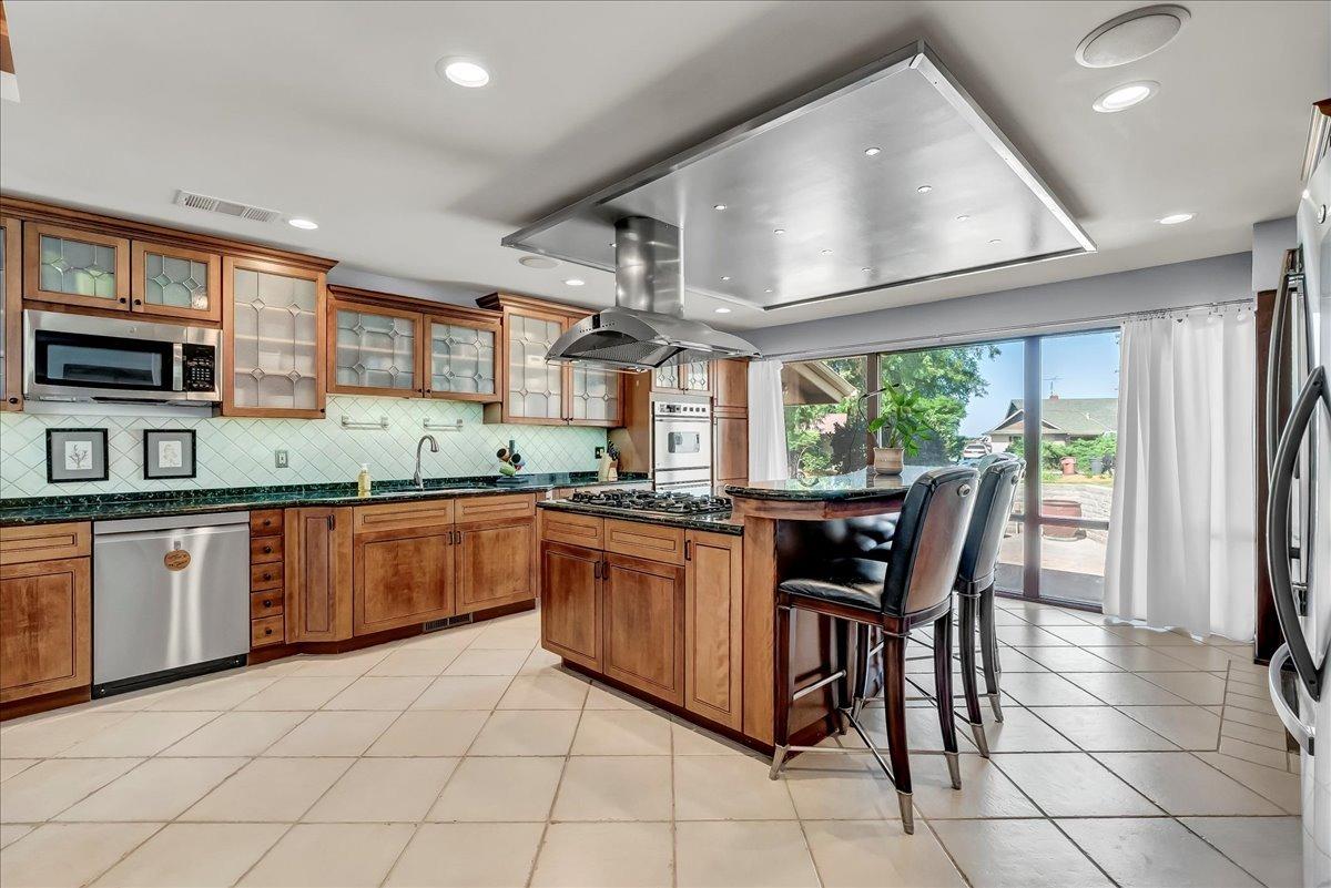 30960 Tower Road Visalia, CA 93292 - Photo 50 of 76 a kitchen with stainless steel appliances granite countertop a stove a sink a dining table and chairs