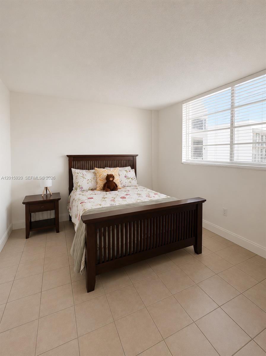 14170 Southwest 84th Street, Unit 404F Miami, FL 33183 - Photo 9 of 18 a bedroom with a bed and a table