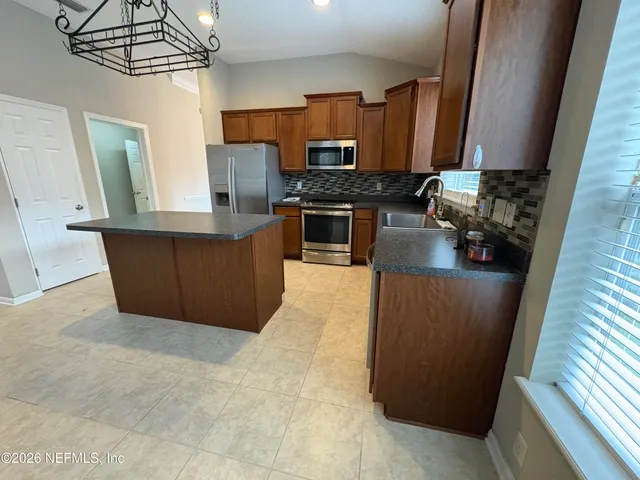 a kitchen with stainless steel appliances a refrigerator a stove a sink a microwave and wooden cabinets