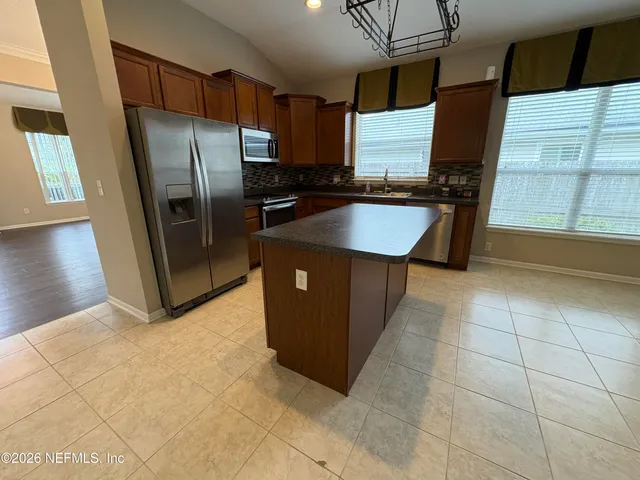 a kitchen with stainless steel appliances granite countertop a refrigerator a stove and a sink