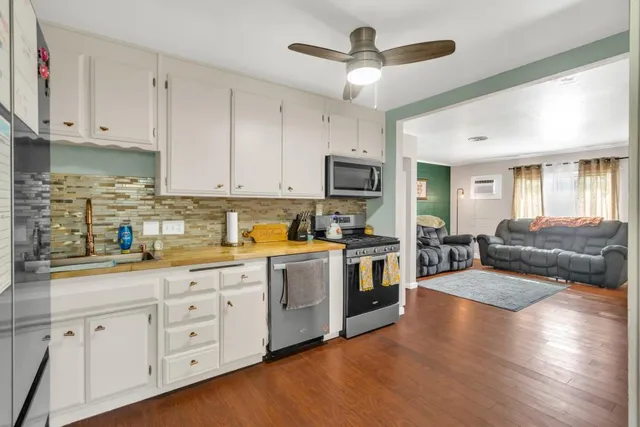 a kitchen with granite countertop a stove a sink and white cabinets