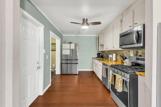 a kitchen with stainless steel appliances a stove top oven a refrigerator a sink and dishwasher with white cabinets