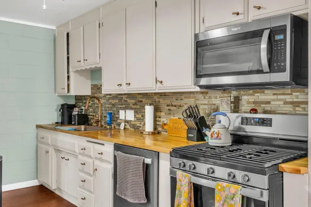 a kitchen with stainless steel appliances granite countertop a stove a sink and a microwave