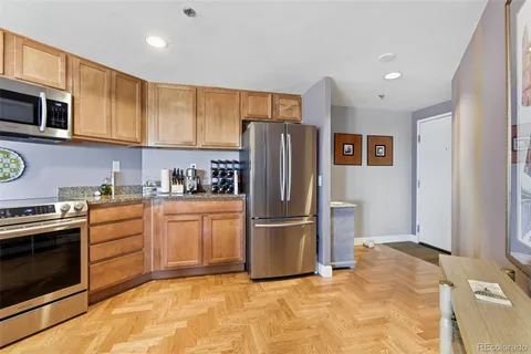 a kitchen with stainless steel appliances granite countertop a stove top oven a sink dishwasher and cabinets with wooden floor