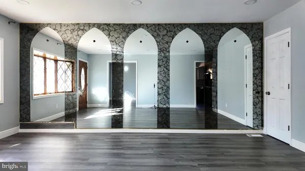 a view of a living room with entryway and wooden floor