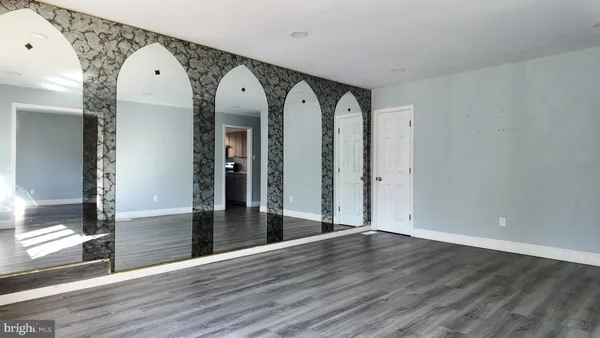 a view of a big room with wooden floor and windows