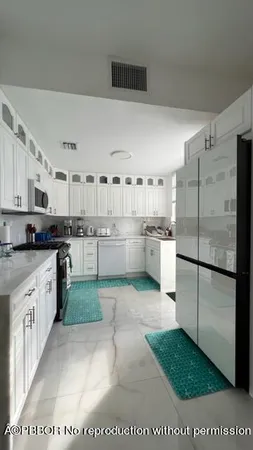 a kitchen with stainless steel appliances granite countertop a refrigerator a stove a sink and a white cabinets