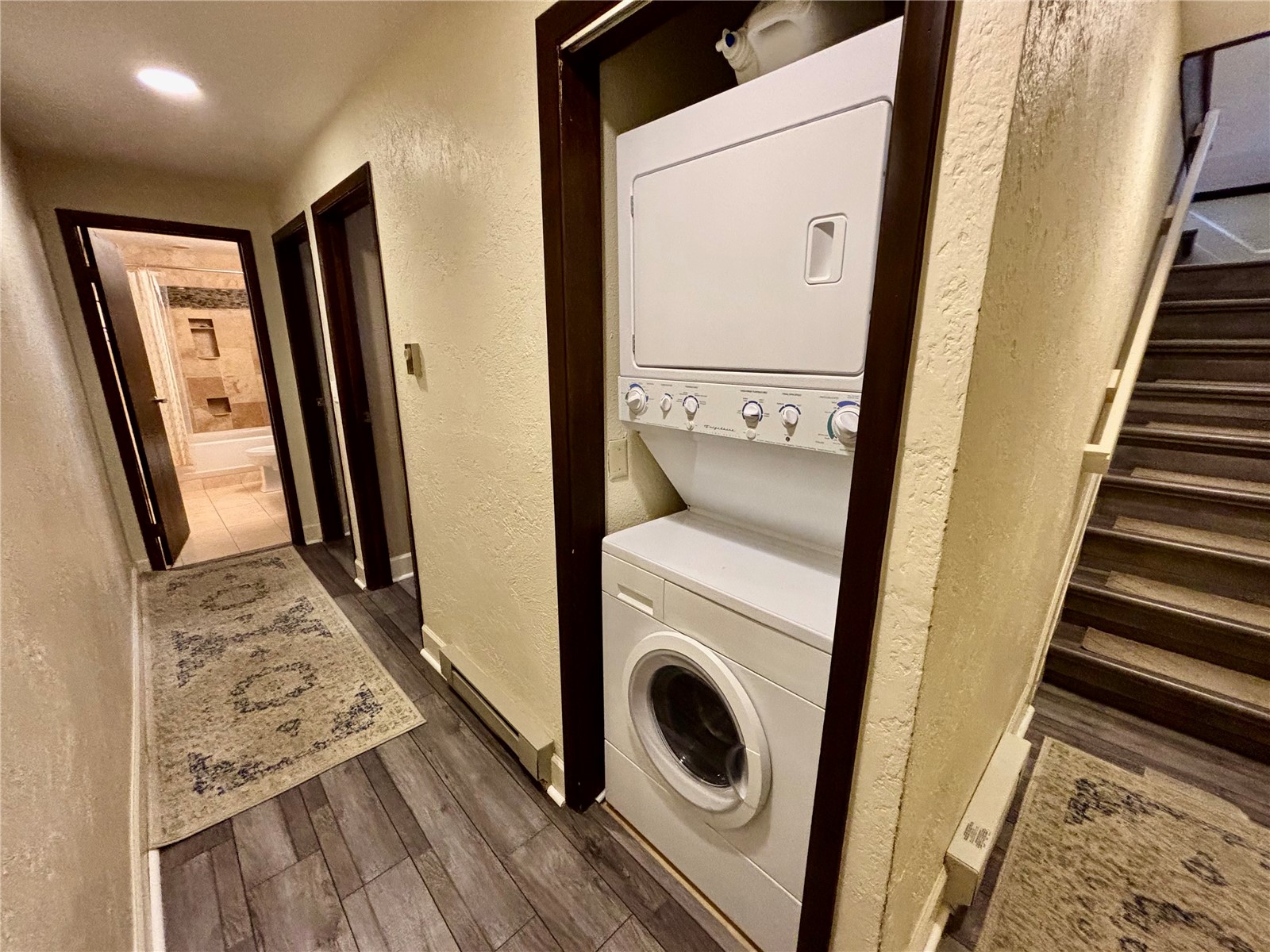 1310 Baldy Road, Unit D Breckenridge, CO 80424 - Photo 16 of 28 Washroom featuring laundry area, baseboards, stacked washer and clothes dryer, a textured wall, and dark wood-type flooring