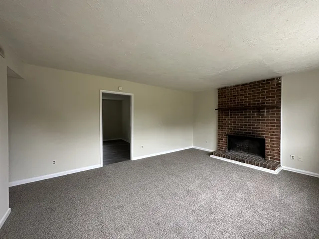 a view of an empty room with a fireplace and a window