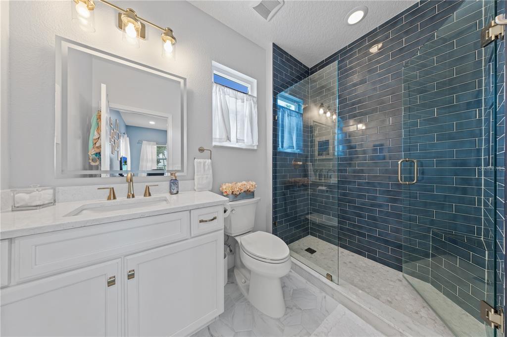 16948 Deer Island Road Tavares, FL 32778 - Photo 35 of 67 a bathroom with a toilet a sink a mirror a shower and vanity